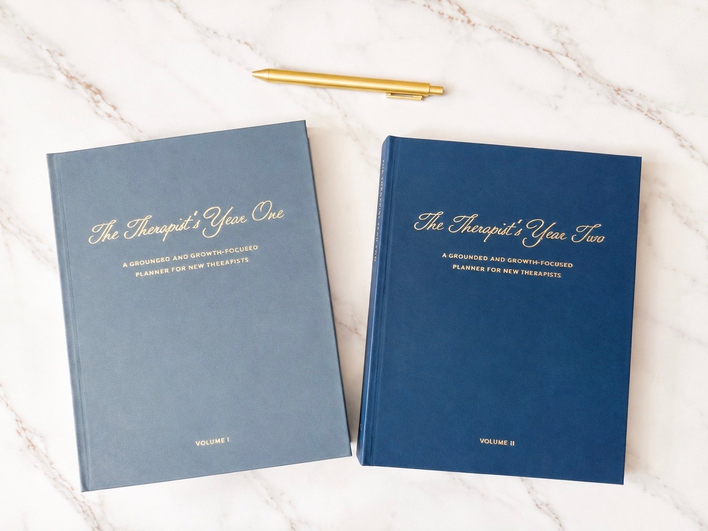 The Therapist's Year One and Year Two planners side by side on a marble surface